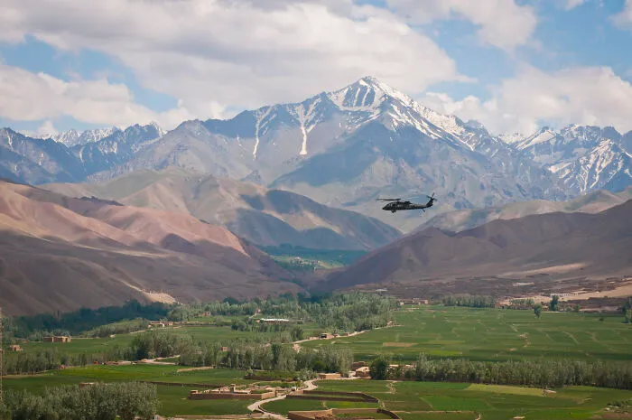 Helicopter flying over lush green valleys with snow-capped mountains, showcasing stunning UNESCO treasures in a remote landscape.