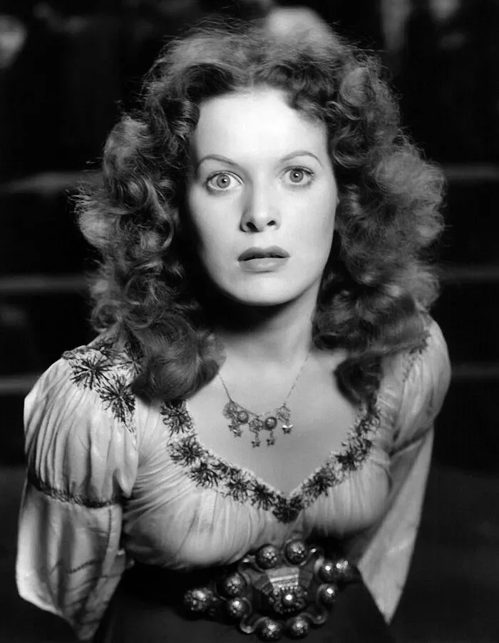 Black and white portrait of a glamorous 1940s icon with curly hair and vintage attire in classic Hollywood style.