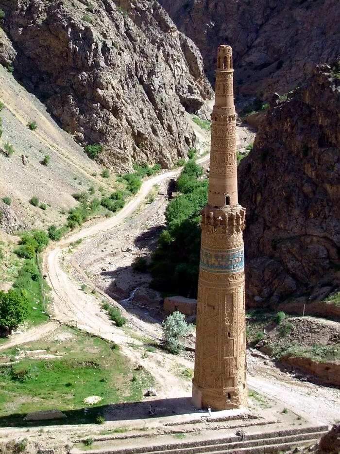 Ancient minaret standing in a rocky valley surrounded by greenery, one of the stunning UNESCO treasures at risk.