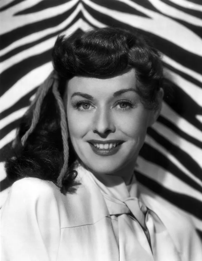 1940s glamorous Hollywood icon smiling with vintage hairstyle and elegant outfit against zebra print background