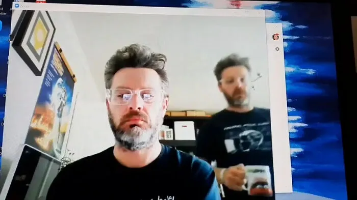Man with glasses and beard on a video call, humorous work-from-home meme setup for remote work survival tips.