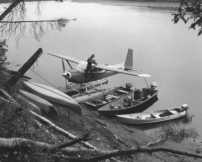 Man On And Float Plane On Shore With Small Boats
