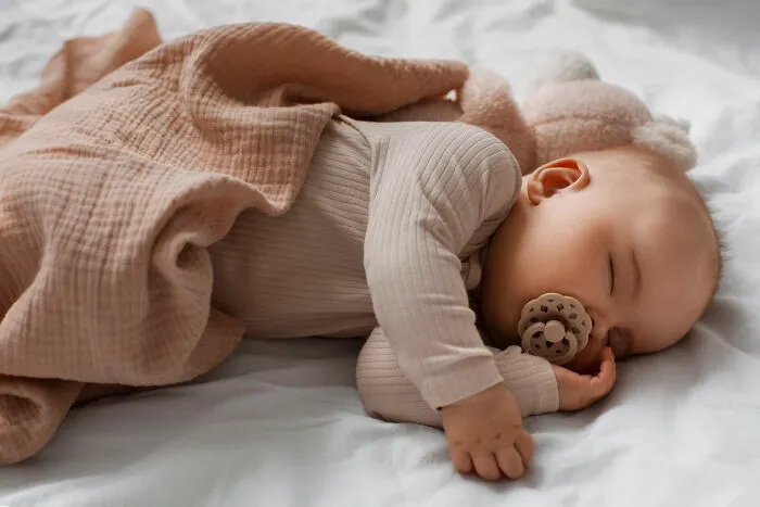 Sleeping baby wrapped in a soft brown blanket, representing unique twins with unusual names like Donwanna and Doneeda.