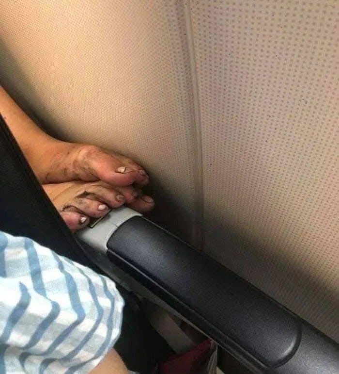 Dirty bare feet resting on an airplane armrest captured in a weird pics or it didn’t happen moment on social media.