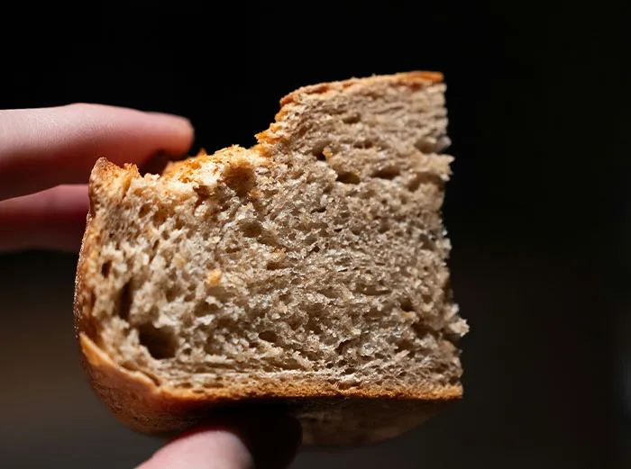 Close-up of a hand holding a piece of bread, illustrating healthy foods dentists and doctors might advise skipping.