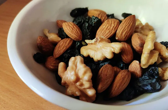 Bowl of mixed nuts and dried fruits representing healthy foods you might want to skip eating according to dentists and doctors online