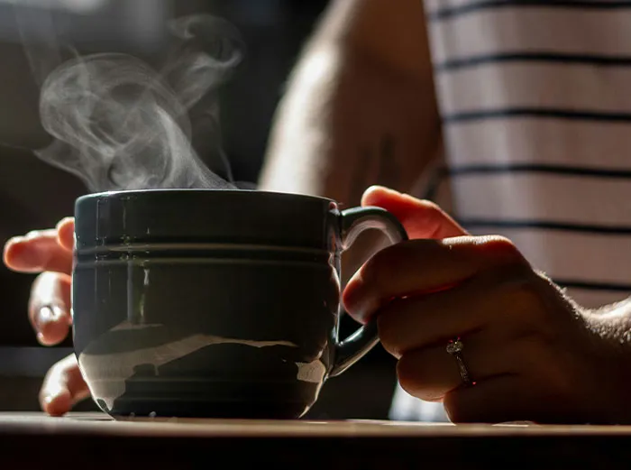 Person holding a steaming cup of hot beverage, illustrating healthy foods you might want to skip eating advice.