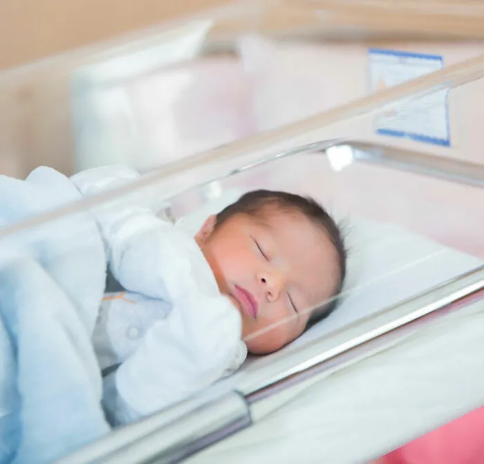 Newborn baby peacefully sleeping in a hospital bassinet, representing twins with unique and crazy names.
