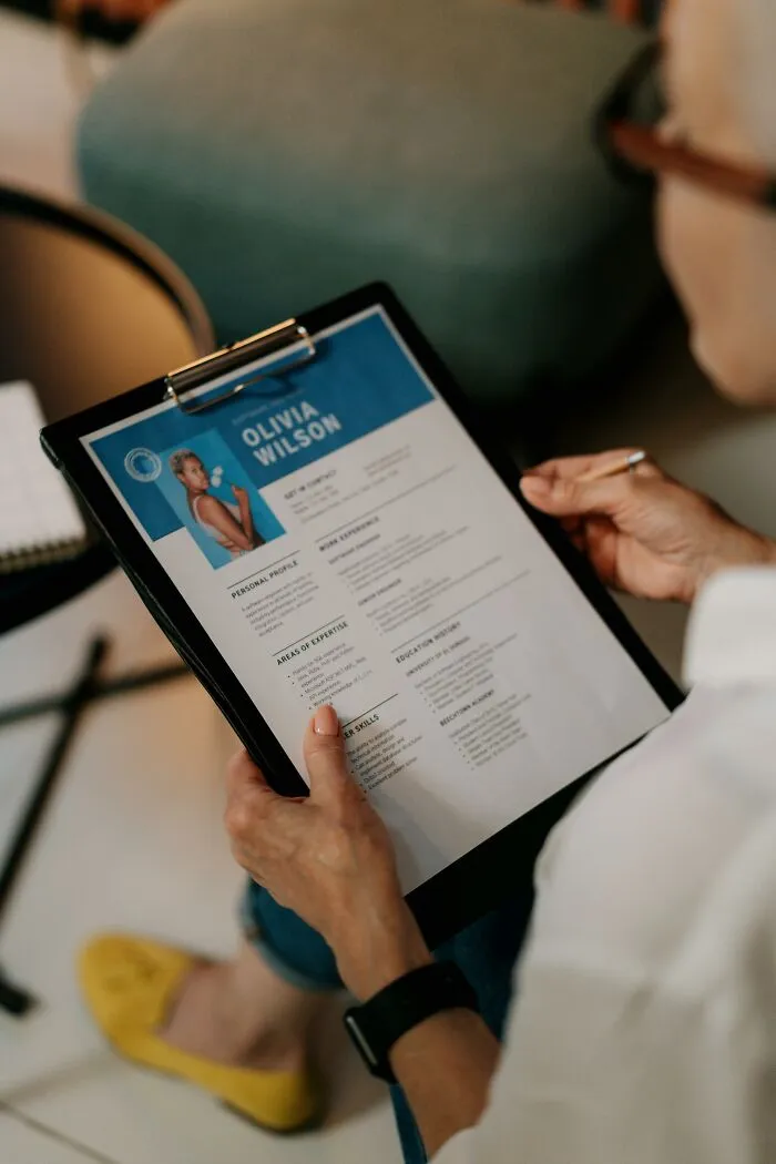 Person holding clipboard reviewing a resume, illustrating out-of-touch moments shared by 93 people recalling ridiculous statements.