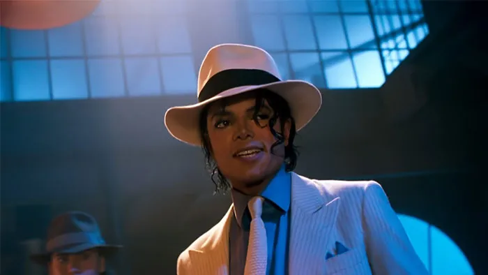 Michael Jackson wearing a white suit and fedora hat, performing under dramatic lighting in a vintage setting.