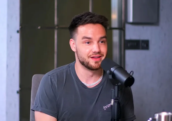 A young man with a beard speaking into a microphone during a podcast discussing Steve Jobs and celebrities.