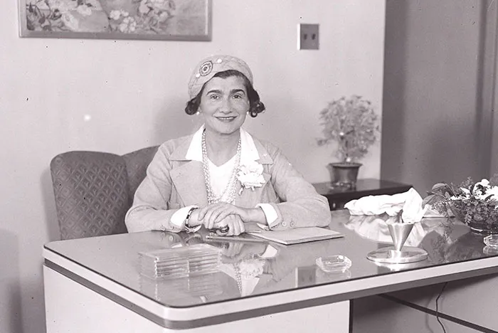 Black and white photo of a smiling woman at a desk, relating to Steve Jobs and controversial celebrity reputations.