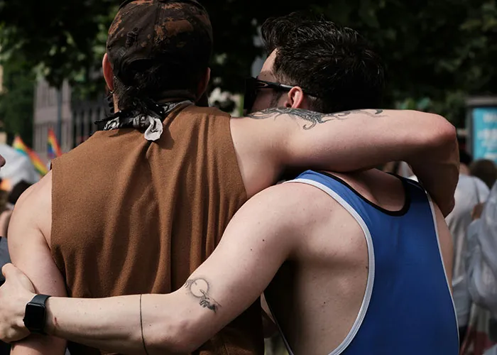Two men embracing each other in a crowd, symbolizing trust and revealing cheating partners in relationships.