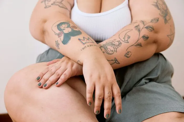 Mujer con tatuajes y uñas pintadas, mostrando actos microfeministas de apoyo entre mujeres en un entorno tranquilo.