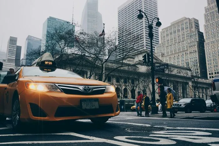 Yellow taxi in a busy city street with tall buildings and pedestrians, illustrating out-of-touch urban experiences.