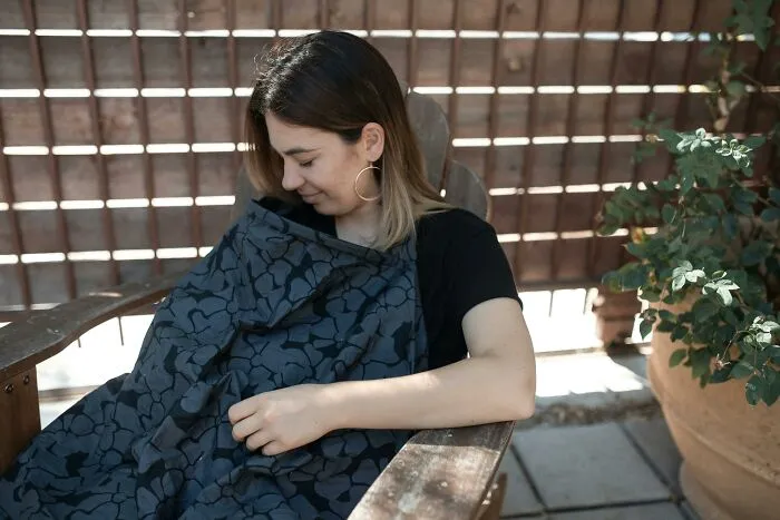 Woman sitting on a bench wrapped in a blanket, looking down thoughtfully, illustrating tech guys finding disturbing computer issues.