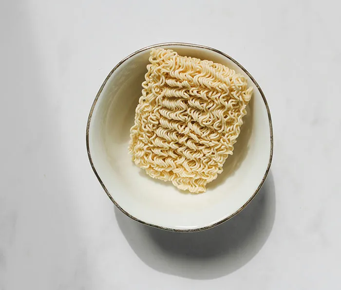 Plato blanco con fideos instantáneos crudos en el centro, ilustrando momentos de personas que se dieron cuenta que su pareja es idiota.