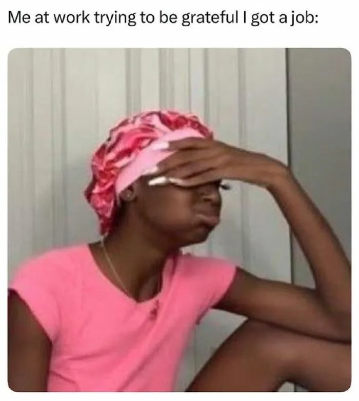 Woman in a pink shirt and bonnet, looking stressed and covering her face, reflecting sarcastic meme about work gratitude.