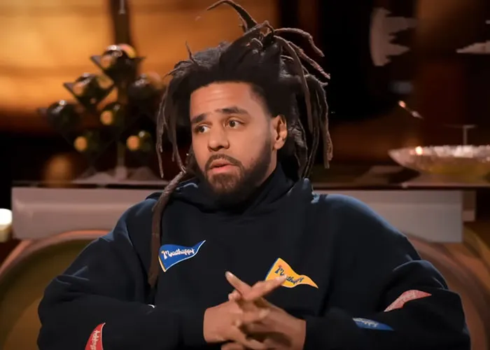 Man with dreadlocks in a dark hoodie sharing stories about people who knew celebrities before fame in an interview setting.