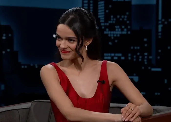 Young woman in a red dress sharing stories about people who knew celebrities before fame on a late-night talk show.