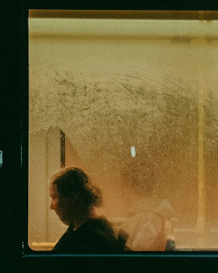 Silhouette of a person inside a bus with a rainy window, capturing a real urban street moment in Helsinki photography.