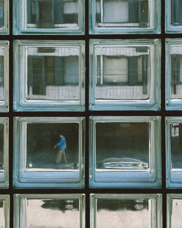 Urban photo of a person walking reflected in glass blocks, capturing real moments on the street in Helsinki.