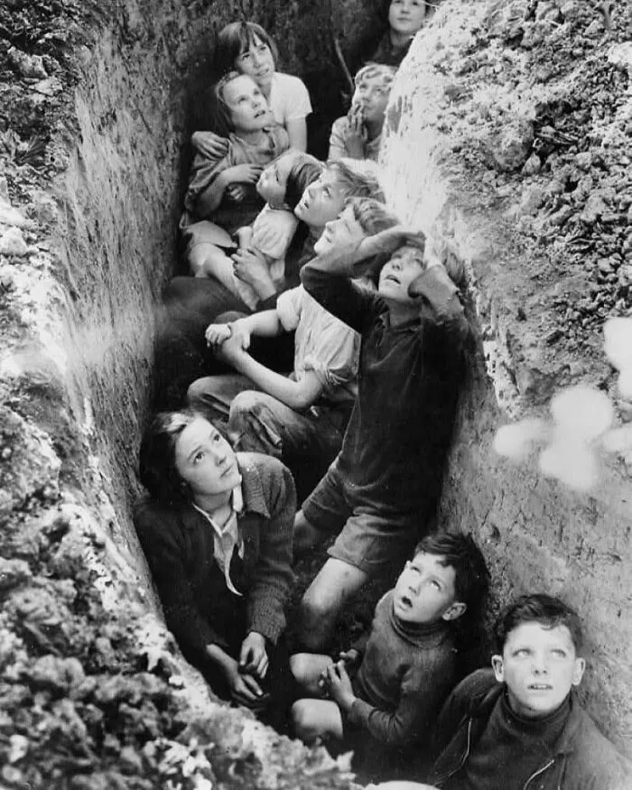 Children hiding in a narrow trench during a historical event, showcasing a fascinating moment from the past.