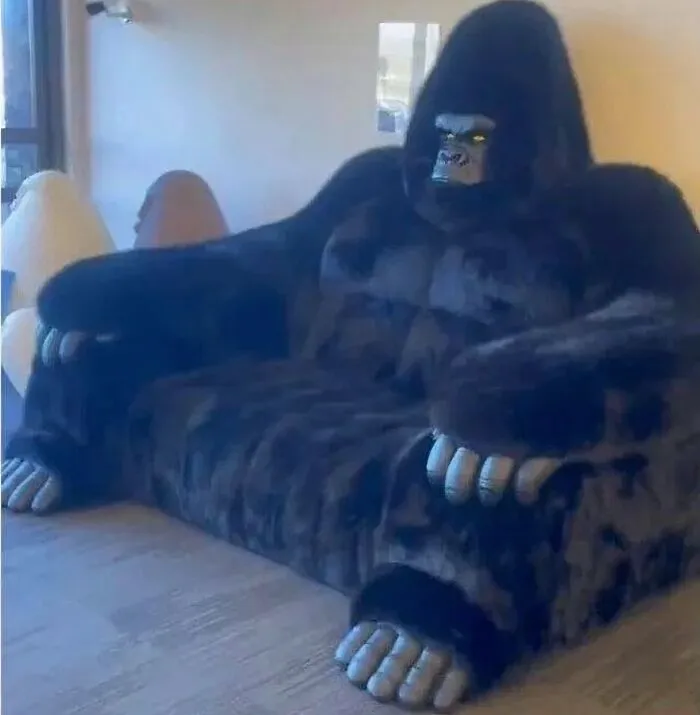 Gorilla-shaped couch with realistic hands and face, an uncomfortable image causing unease without clear reason.