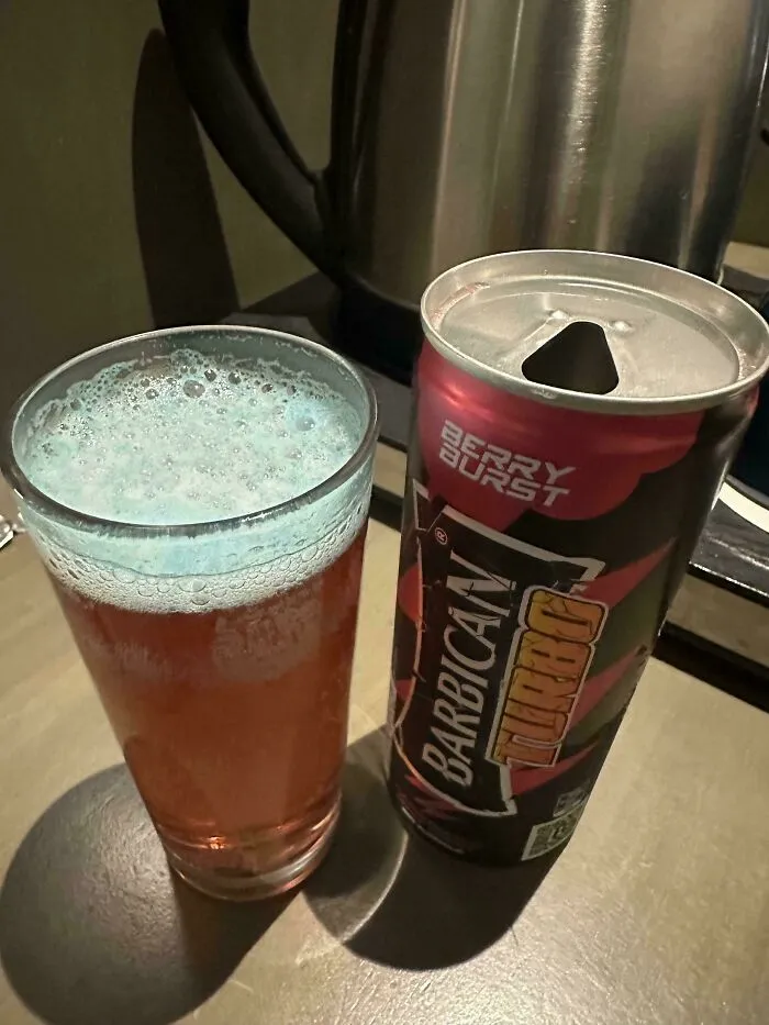 Open can of Barbican Turbo Berry Burst drink next to a glass filled with foamy beverage showing airport security item concerns.