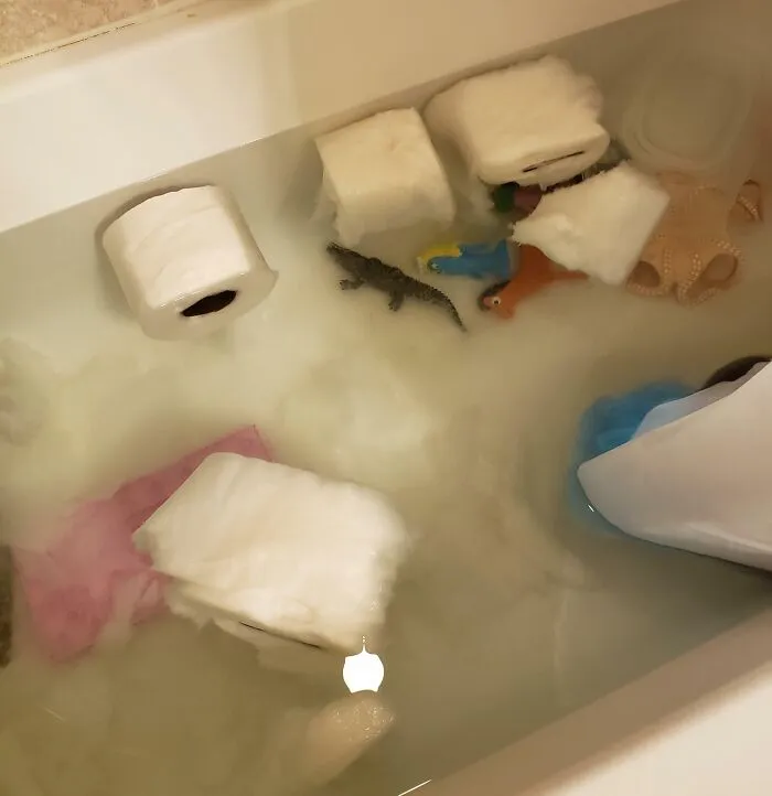 Padres y madres enfrentan un día peor con juguetes y papel higiénico flotando en agua dentro de una bañera.