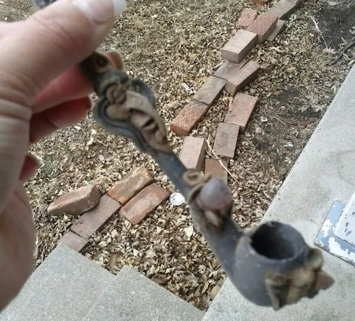 Hand holding an old, decorative pipe found among unexpected things hidden in walls and other home places.