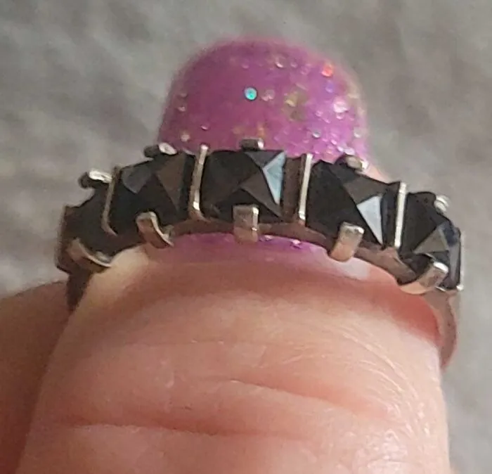 Close-up of a ring with black stones found unexpectedly in walls and other hidden places in people’s homes.