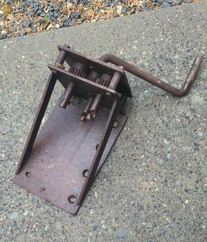 Mecanismo de torsión de hierro pesado, de unos 4.5 kg, oxidado y, por lo tanto, de color óxido. La manija gira los tres husos en la misma dirección. Base de unos 30 x 20 cm sin manija. ¿Para qué podría haberse utilizado?