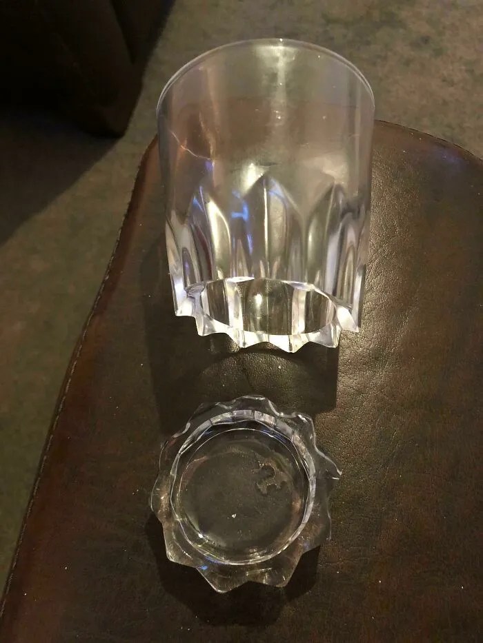 Glass and its matching base separated, creating a confusing funny pic of a broken cup shape on a dark surface.
