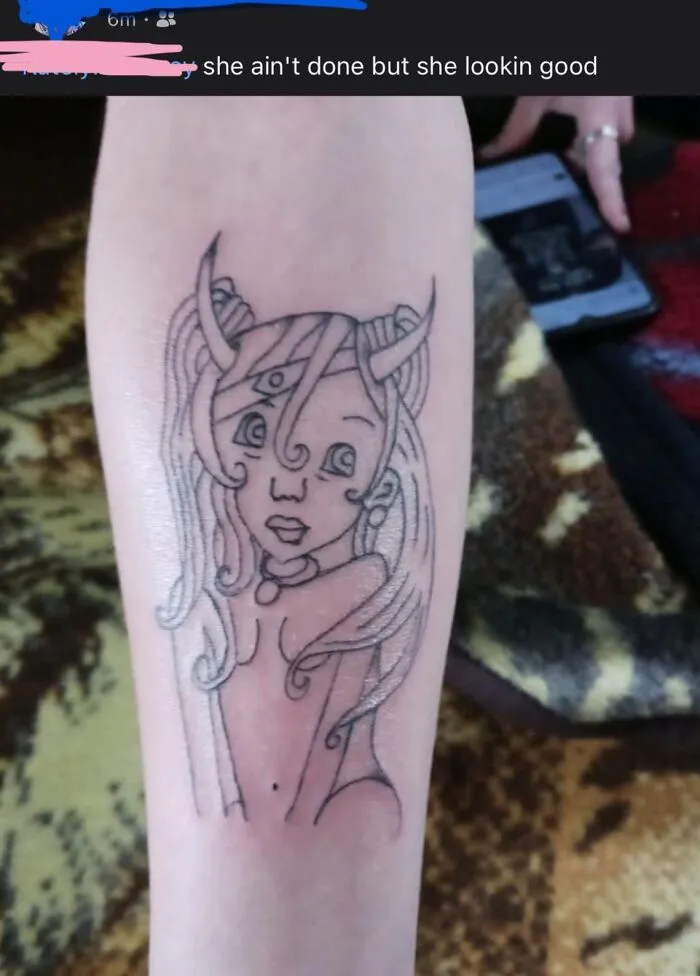 Outline tattoo of a girl with horns and a third eye on forearm, an example of hilariously bad tattoos from inkshaming collection.