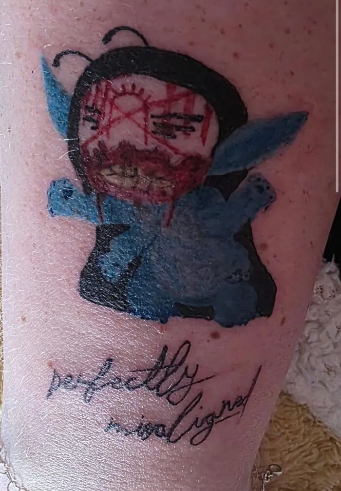 Poorly drawn blue cartoon tattoo with misspelled text as an example of hilariously bad tattoos.