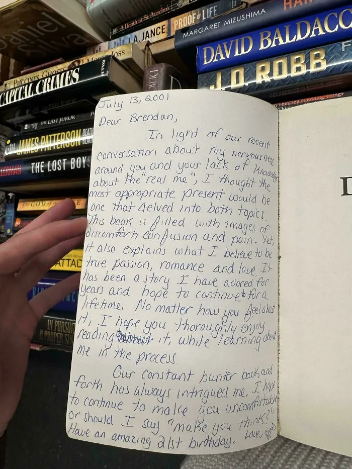 Handwritten letter inside a book found among historical mementos and old novels, revealing a personal message from 2001.