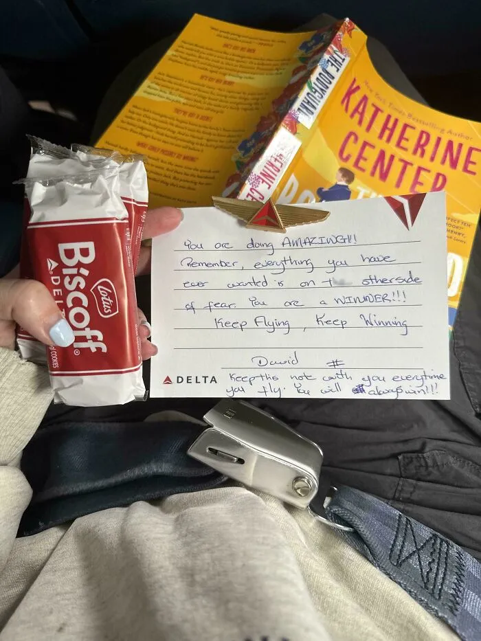 Hand holding Biscoff cookie and a motivational note from Delta airline, inspiring those with fear of flying to keep flying.