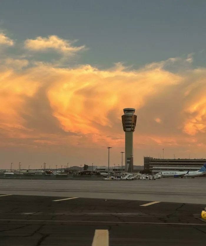 Airport control tower at sunset with planes on the tarmac, symbolizing overcoming fear of flying and inspiring travel.