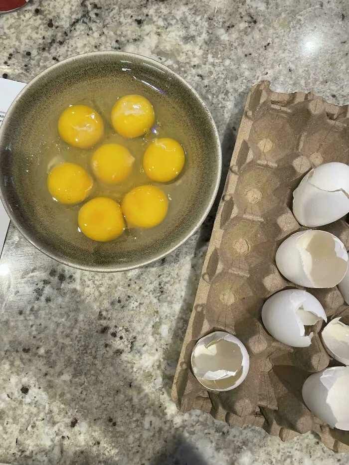 Bowl with seven egg yolks next to cracked eggshells on a counter, reflecting internet lies made hilariously absurd.