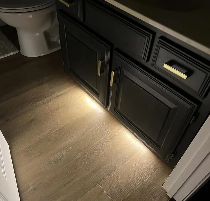 Under-cabinet lighting illuminating wood flooring in a bathroom, showcasing trending products in the Pandaverse virtual market.