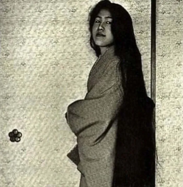 Vintage photo of a woman in traditional clothing with extremely long hair, capturing a weird thing about history.