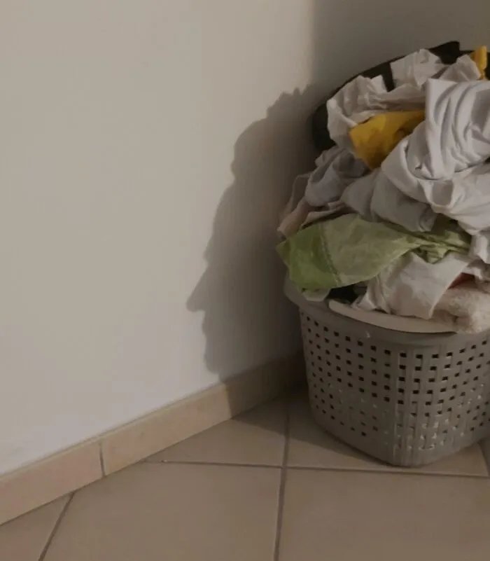 Shadow resembling a face cast on a wall by a laundry basket filled with clothes, showcasing a cool and interesting shadow effect.
