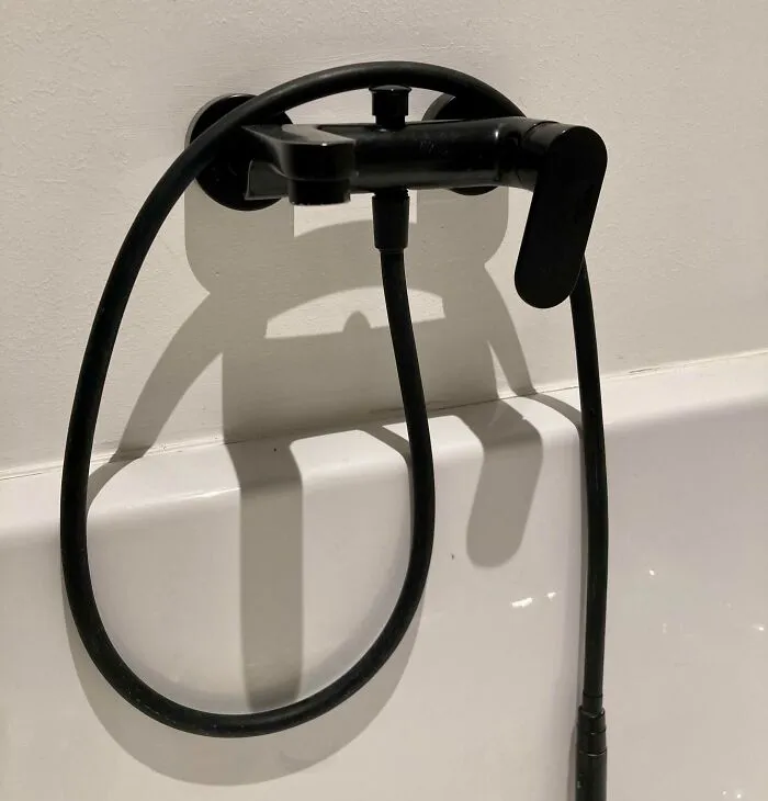 Bathroom faucet and hose casting a cool and interesting shadow that looks like a face, highlighting bizarre shadows effects.