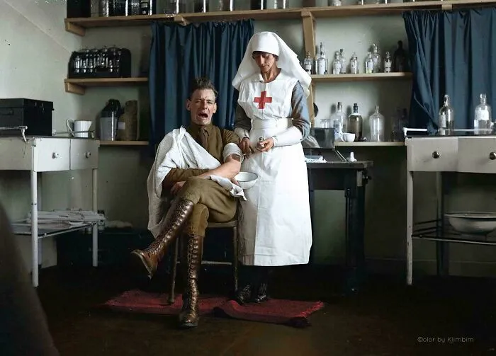 Colorized history pic of a World War I soldier receiving medical treatment from a nurse in a vintage clinic setting.