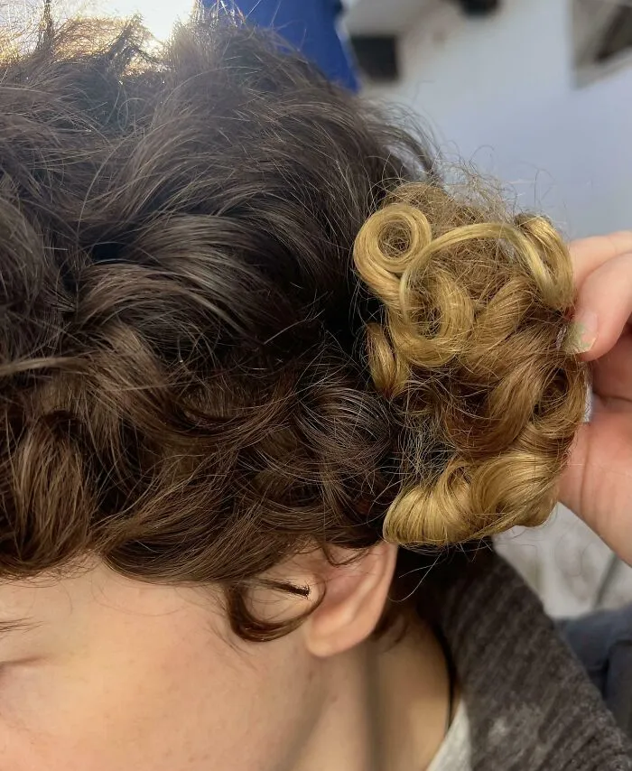 Comparación de mechones de cabello rizado en dos colores diferentes, mostrando contraste visual llamativo.