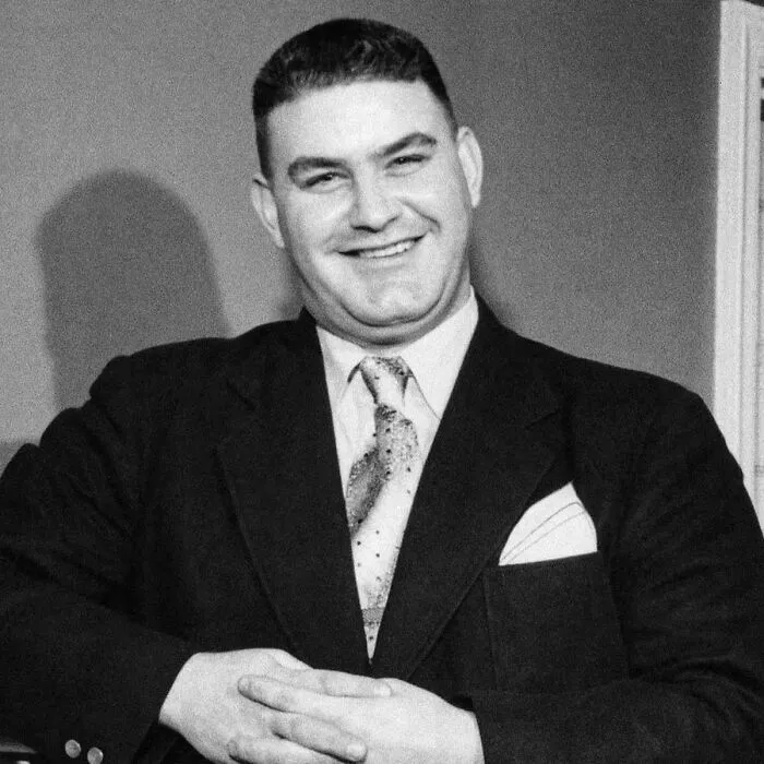 Smiling man in vintage suit and patterned tie, showcasing fascinating content on the internet with engaging and interesting facts.
