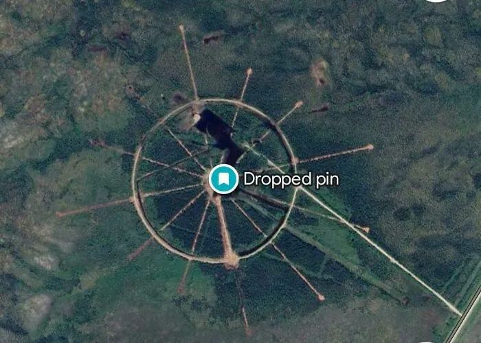 Aerial view of a mysterious circular structure captured on Google Maps showing unique shenanigans in a forested area.
