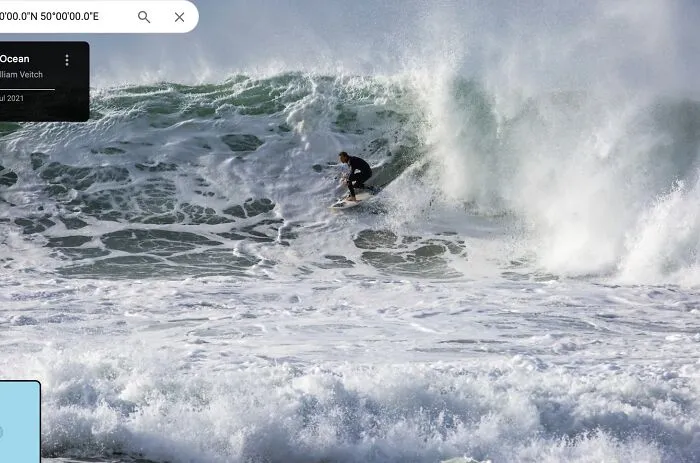 Surfer riding large ocean wave captured in a screenshot from Google Maps showcasing shenanigans at the beach.