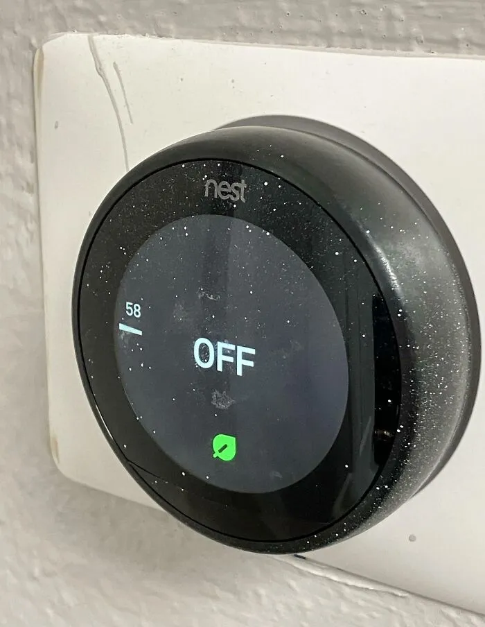 Termostato Nest apagado con polvo acumulado en una pared, ejemplo de lugar de trabajo tóxico y deteriorado.